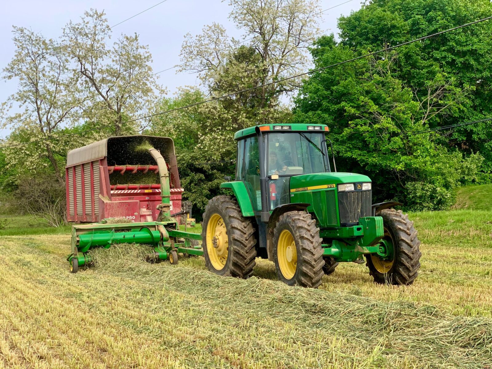 Green tractor with hay wagon harvesting in Lancaster, PA during spring.